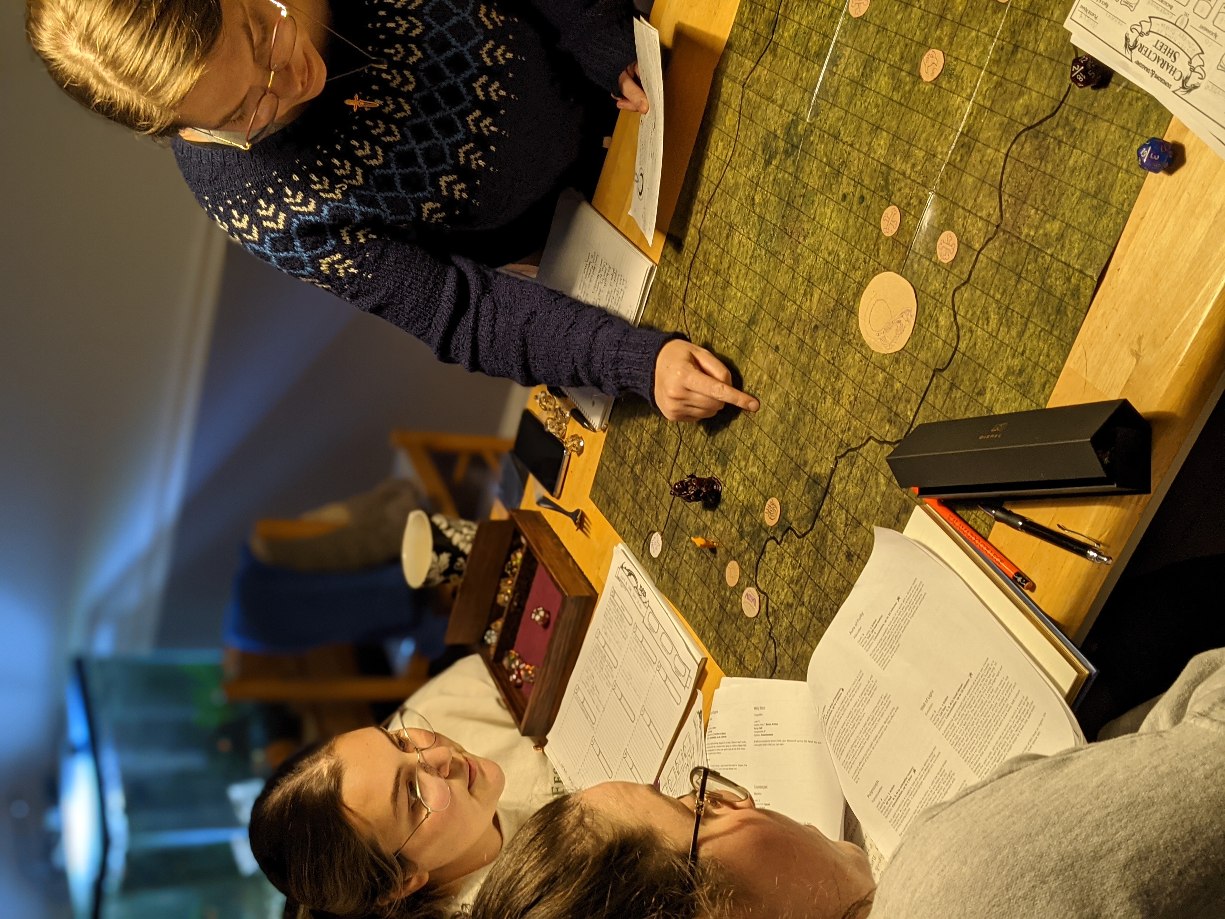 Three young adults pointing at a DnD map.