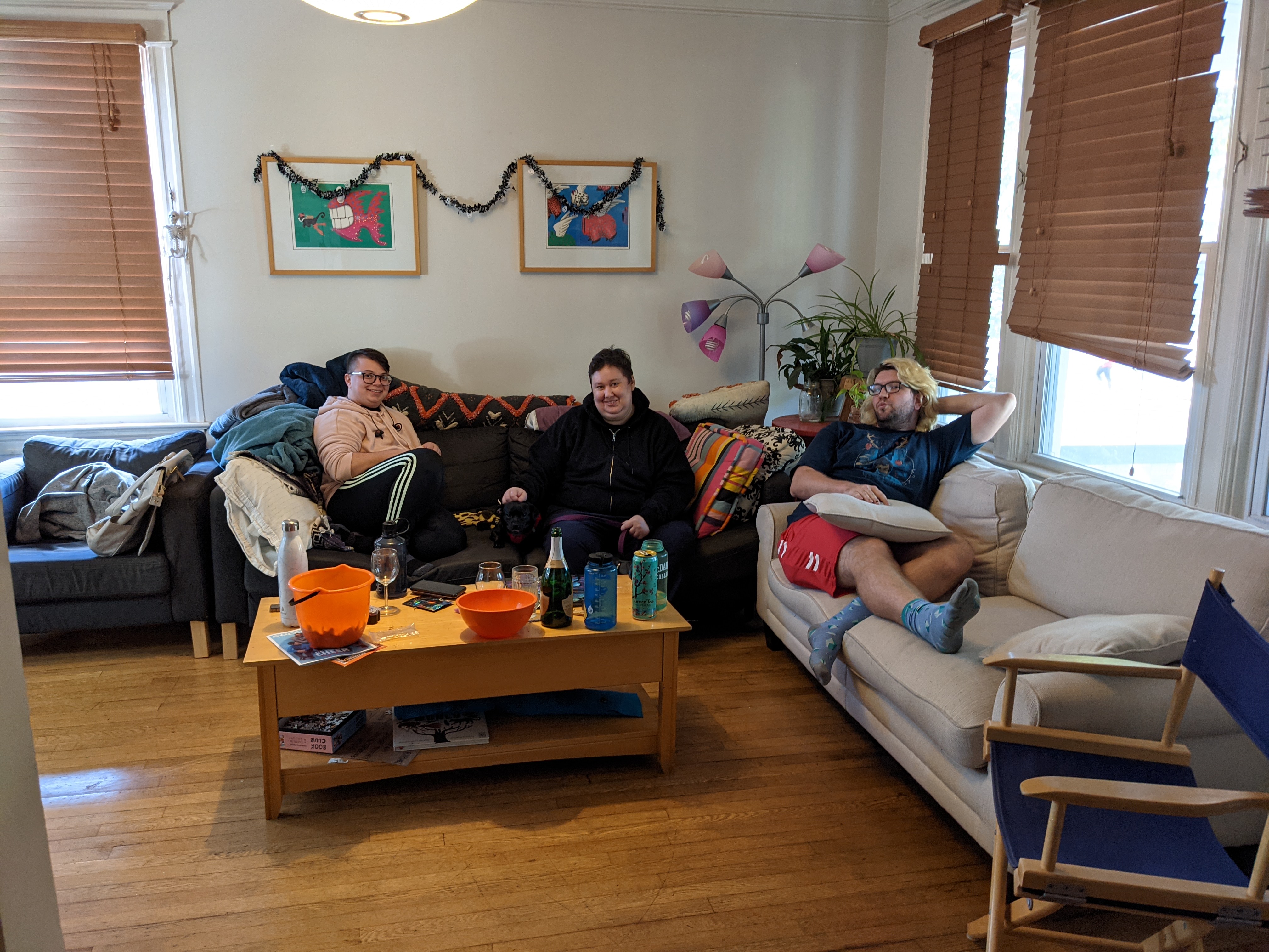 Three people sitting in a living room with two couches.