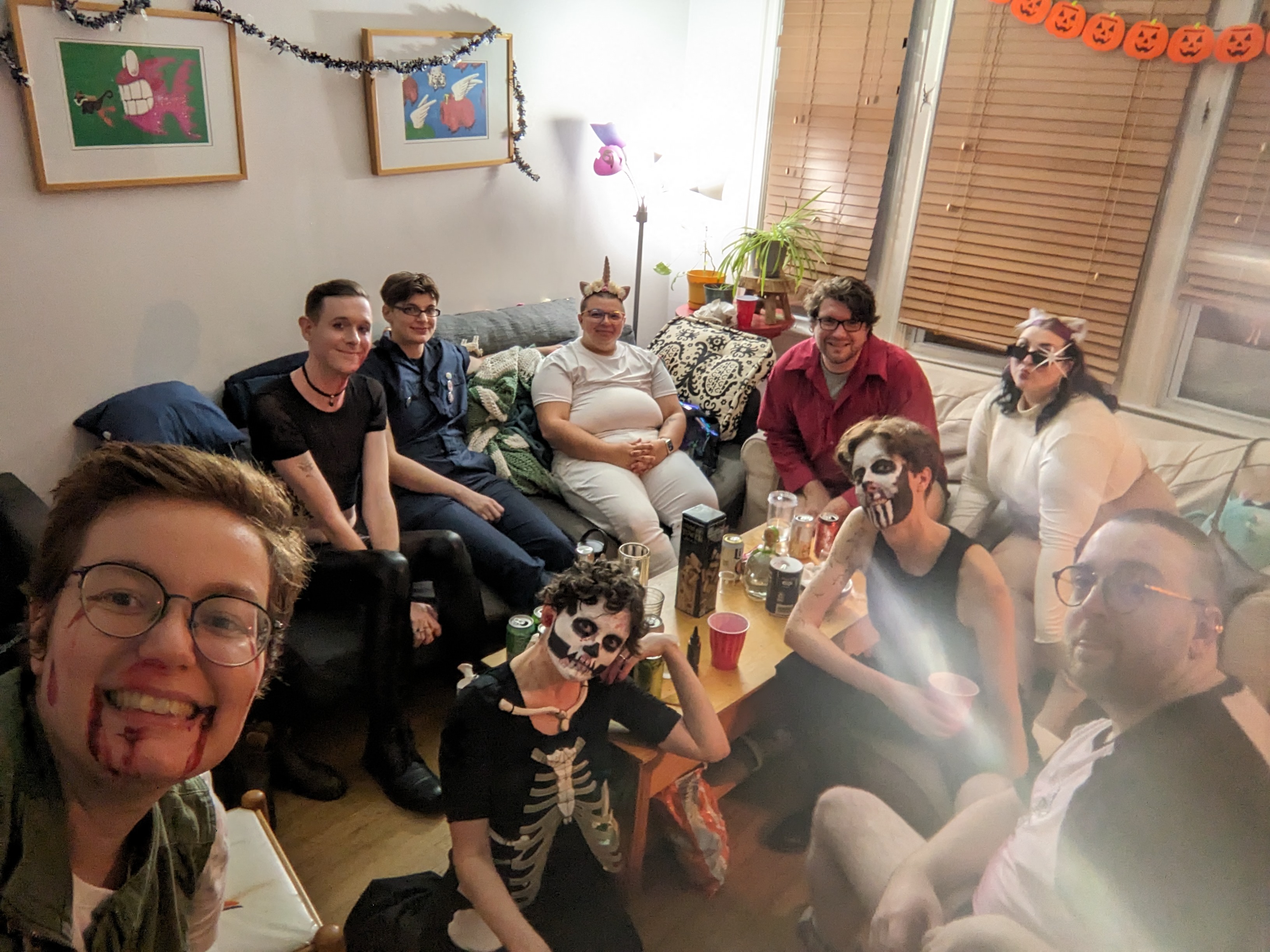 A group of people in halloween costumes sitting on couches in a living room.